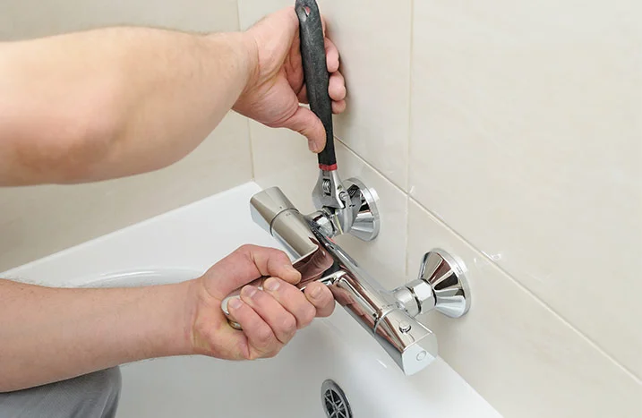 Person montiert Wasserhahn mit Schraubenschlüssel.